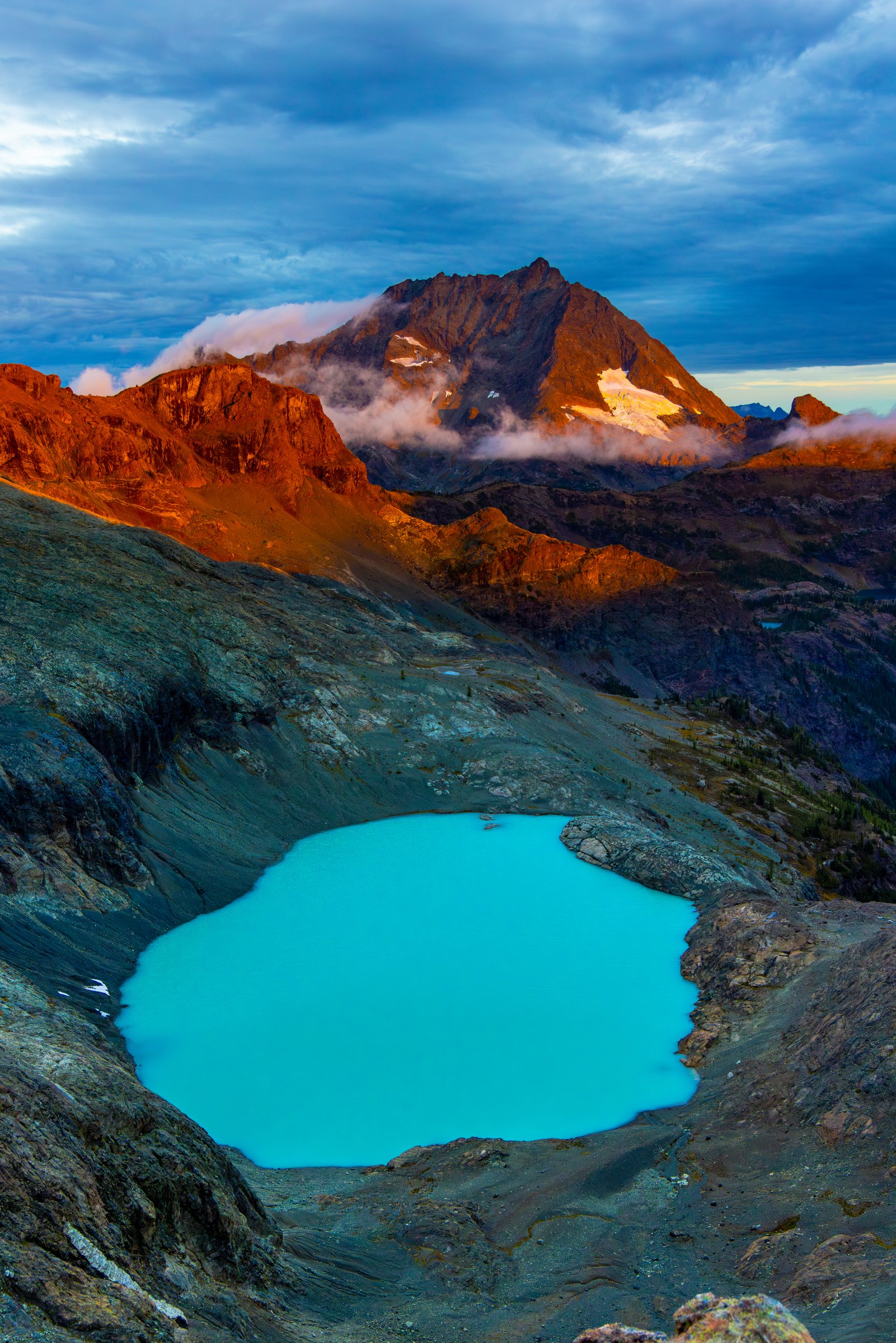 Turquoise alpine lake below red and grey peaks