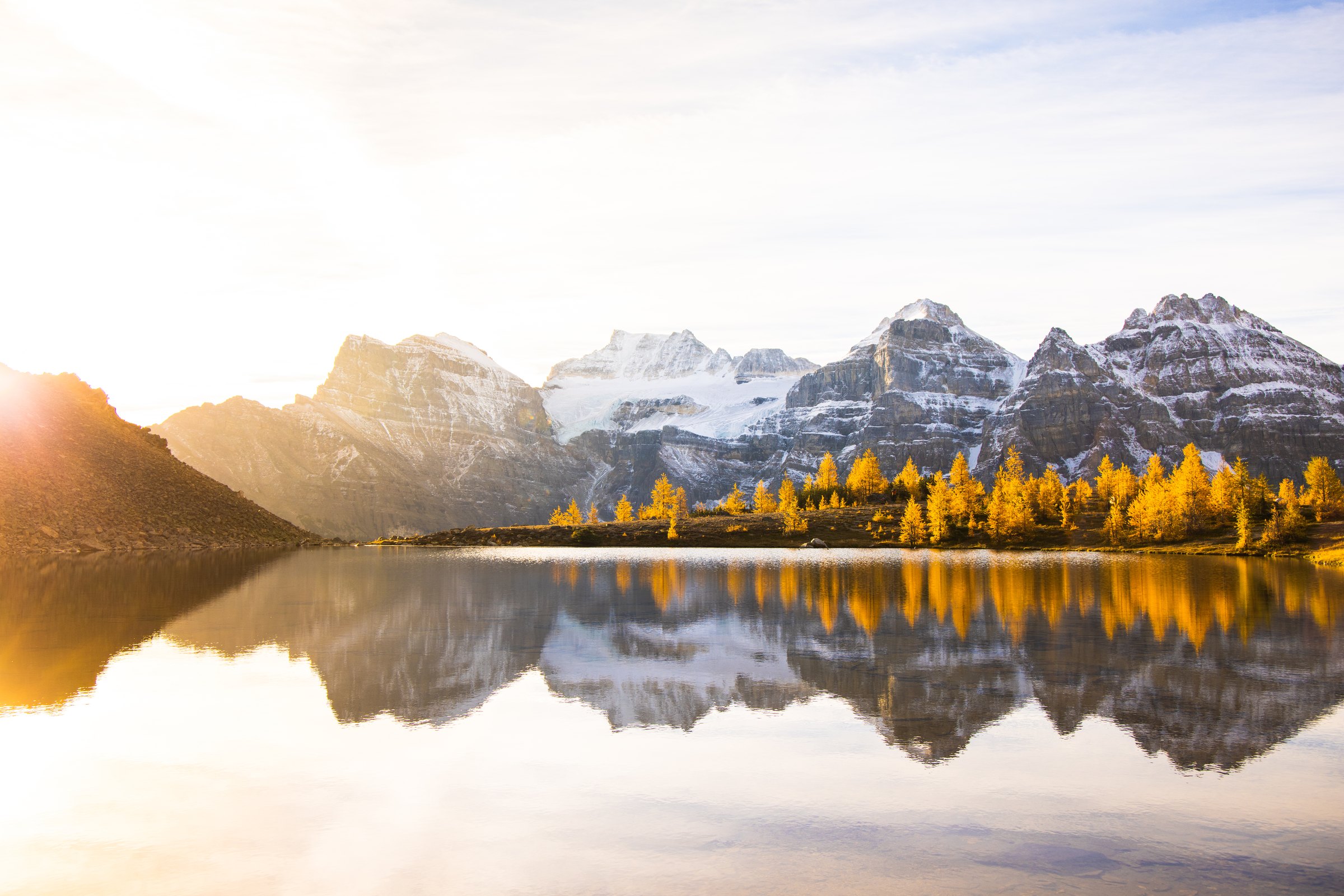 Snowy peaks and golden trees reflected in a glassy mountain lake in the Canadian Rockies